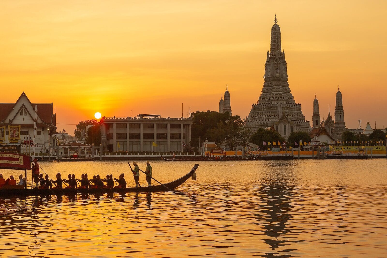 Wat Arun and a royal barge on the Chao Phraya River at sunset
